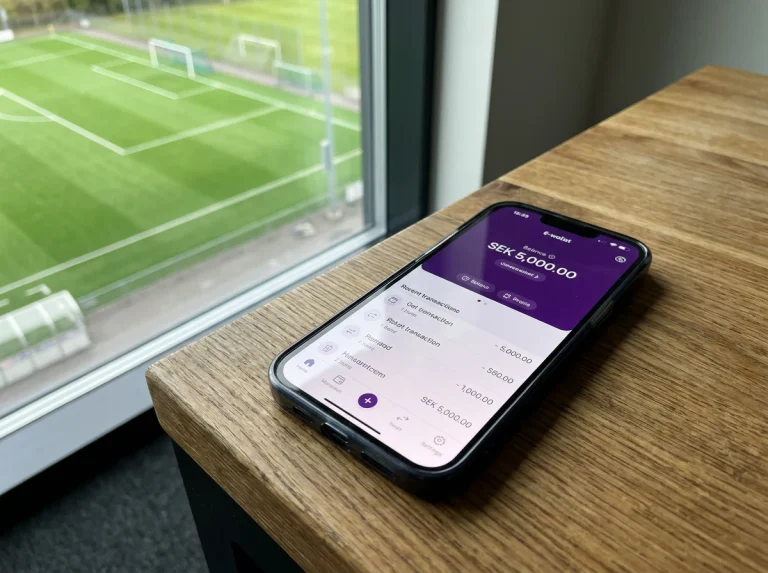 Smartphone med Skrill-appen öppen bredvid en grön fotbollsplan